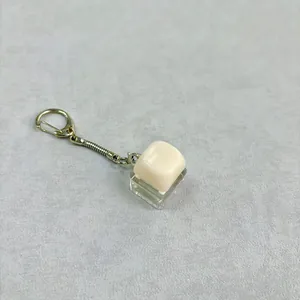 Detailopname van een crème-kleurige toetskap sleutelhanger met een glanzende finish
