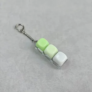 Macrodetail van glanzende groene en witte hars keycap fidget knoppen aan een sleutelhanger