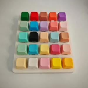 Top view of a 5x5 grid of colorful mechanical keyboard keycaps on a white base