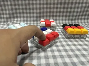 Hand drückt ein farbenfrohes 9-Tasten-Mechanikschalter-Tester-Fidget-Spielzeug auf Karomuster