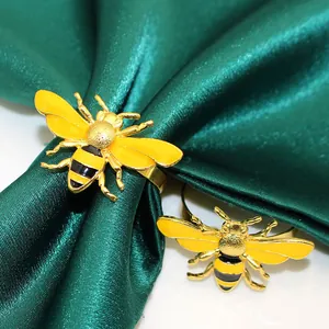 Detail shot of yellow bee napkin ring with gold-tone finish on green satin fabric