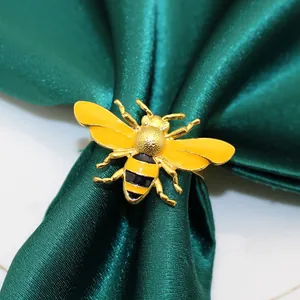 Detail view of a decorative yellow bee napkin ring on a dark green satin napkin.