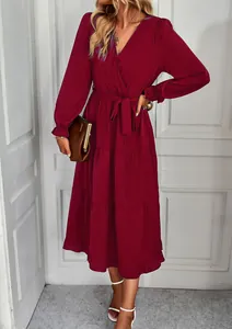 Detail view of the tiered skirt and waist tie on this burgundy long sleeve midi dress