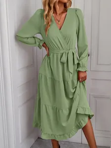 Detail view of a sage green V-neck tiered maxi dress with long sleeves and a waist tie