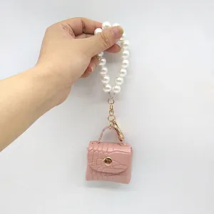 Primer plano de un mini llavero de bolso rosa con efecto cocodrilo y perlas.