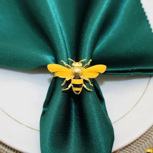 Macro detail of a yellow enamel bee napkin ring placed on a premium green satin napkin
