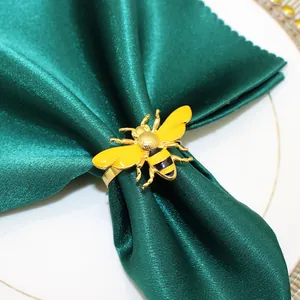 Macro detail of yellow enamel bee napkin ring on a dark green satin napkin decoration