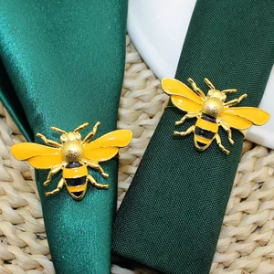 Detailed view of yellow enamel bee napkin rings on green fabric napkins
