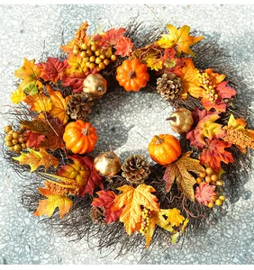 Overhead view of a fall harvest wreath featuring orange pumpkins, maple leaves, and pinecones.