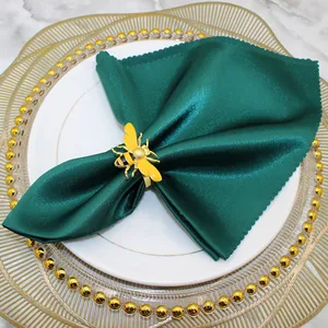 Close-up of a decorative yellow bee napkin ring on a green satin napkin