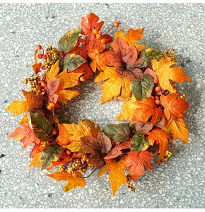 Close-up view of an autumn harvest wreath featuring orange maple leaves and small berries.