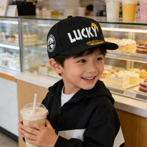 Jonge jongen die een zwarte LUCKY pet met geborduurde kroon draagt in een café