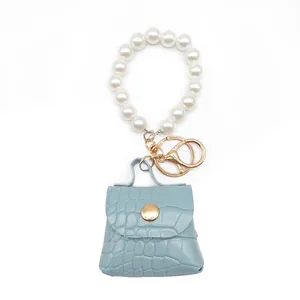 Detalle de un mini llavero de bolso azul con textura de cocodrilo y elegantes perlas blancas