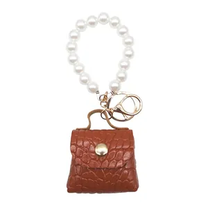 Primer plano de un mini llavero de bolso marrón con estampado de cocodrilo y perlas blancas