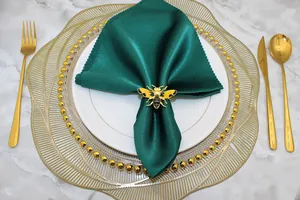 Detailed view of a yellow bee napkin ring on an emerald green satin napkin.