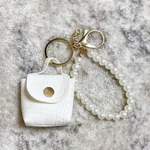 Vista detallada del llavero mini bolso blanco con patrón de cocodrilo y correa de perlas