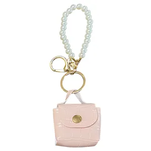 Vista detallada de llavero mini bolso rosa con relieve de cocodrilo y correa de perlas