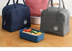 Geïsoleerde Oxford lunchtassen met beertjeslogo naast een gezonde maaltijddoos