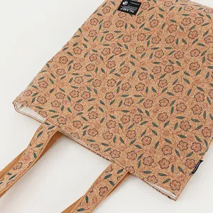 Close-up detail of eco-friendly cork tote bag with vintage floral print and brand label.