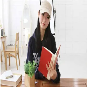 Young woman wearing a stylish beige flat-top military cap in a casual indoor setting.