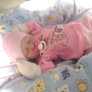 Close-up of 19-inch realistic reborn baby doll with pink outfit and pacifier sleeping
