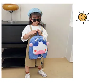 Adorable mochila azul de vaca de dibujos animados para niños, llevada por un niño real
