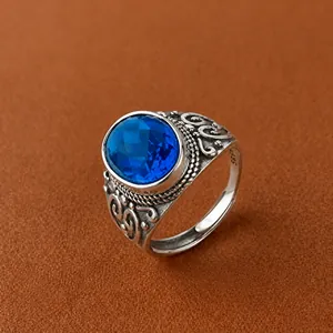 Detailansicht eines verzierten Vintage-Silberrings mit ovalem blauem Edelstein und Gravur.