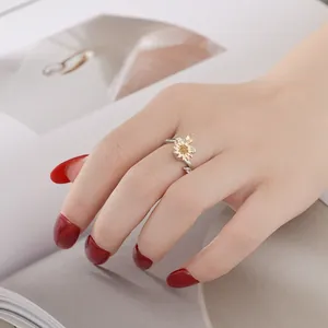 Nahaufnahme eines rotierenden Sonnenblumenrings mit gelbem Zirkonia an gepflegter Hand