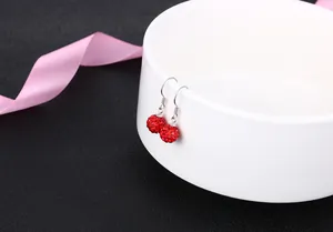 Close-up of red crystal ball drop earrings with S925 silver hooks hanging on a bowl.