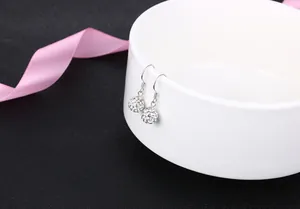 Detailed view of elegant S925 sterling silver crystal disco ball hook earrings on a white bowl.