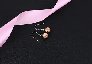 Close-up of sparkling rose gold crystal ball earrings featuring polished silver hooks
