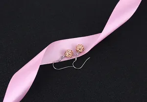 Close-up of sparkling rose gold crystal ball earrings with pink satin ribbon detail