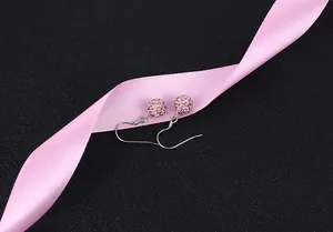 Close-up of pink crystal Shamballa ball earrings on silver hooks with satin ribbon