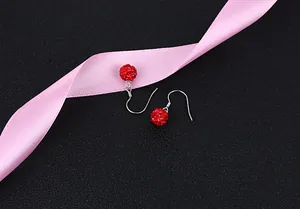 Close-up of sparkling red crystal ball dangle earrings with silver hooks on black