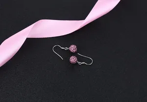 Macro view of pink crystal Shamballa drop earrings with S925 silver hooks on black surface