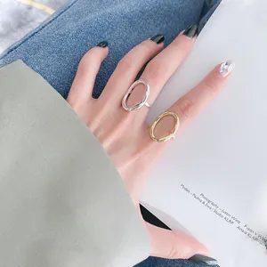 Makroansicht von minimalistischen, unregelmäßigen Gold- und Silberringen an der Hand