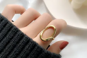 Detailansicht eines stilvollen, goldenen, unregelmäßigen, hohlen, offenen Rings am Finger