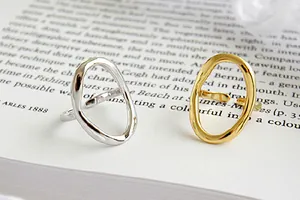 Nahaufnahme von unregelmäßigen geometrischen Ringen in Silber und Gold auf einem Buch.