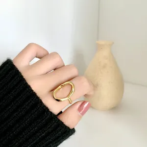 Detailansicht eines unregelmäßigen hohlen goldenen Rings am Zeigefinger mit Pullover