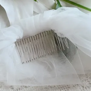 Macro view of delicate white tulle bridal veil with integrated silver metal comb
