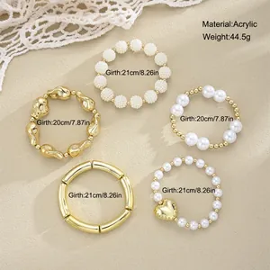 Detailed view of acrylic irregular gold bracelet set with pearls and heart charm decoration