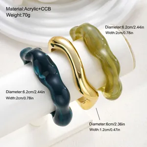 Close-up of acrylic and gold finish irregular bangle set with size details