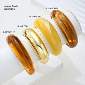 Close-up detail view of acrylic and gold chunky bangles set with diameter dimensions