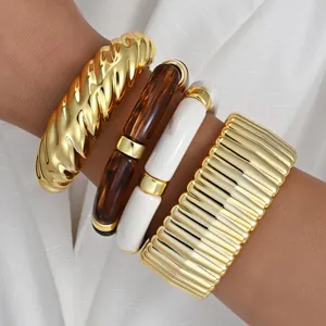 Chunky gold and acrylic bangle set worn on a model's wrist with elegant white background
