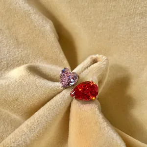 Détail d'une bague en argent S925 avec une pierre cœur rose et une larme rouge.