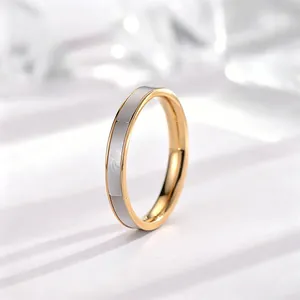 Gedetailleerde close-up van een minimalistische gouden titanium ring met witte schelp