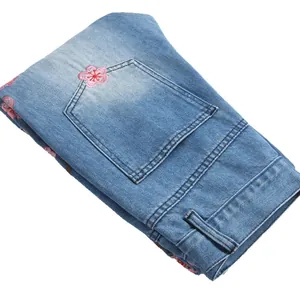 Men's slim fit flare jeans featuring delicate pink plum blossom embroidery on light blue denim.