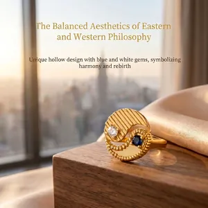 Close-up of a gold Yin Yang ring with inlaid blue and white gemstones on a wooden stand.