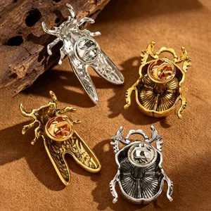 Macro view of metal beetle and cicada lapel pins showing the butterfly clutch back