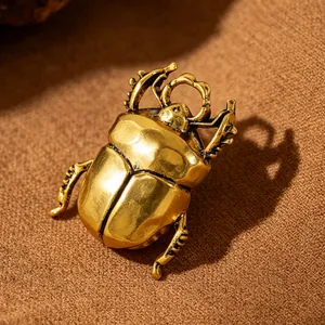 Detailed close-up showing the vintage gold-tone metallic beetle ring on textured brown cloth